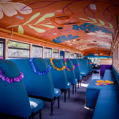 Interior of the Crawler Hauler party bus with hand-painted tropical ceiling and leis on the seats